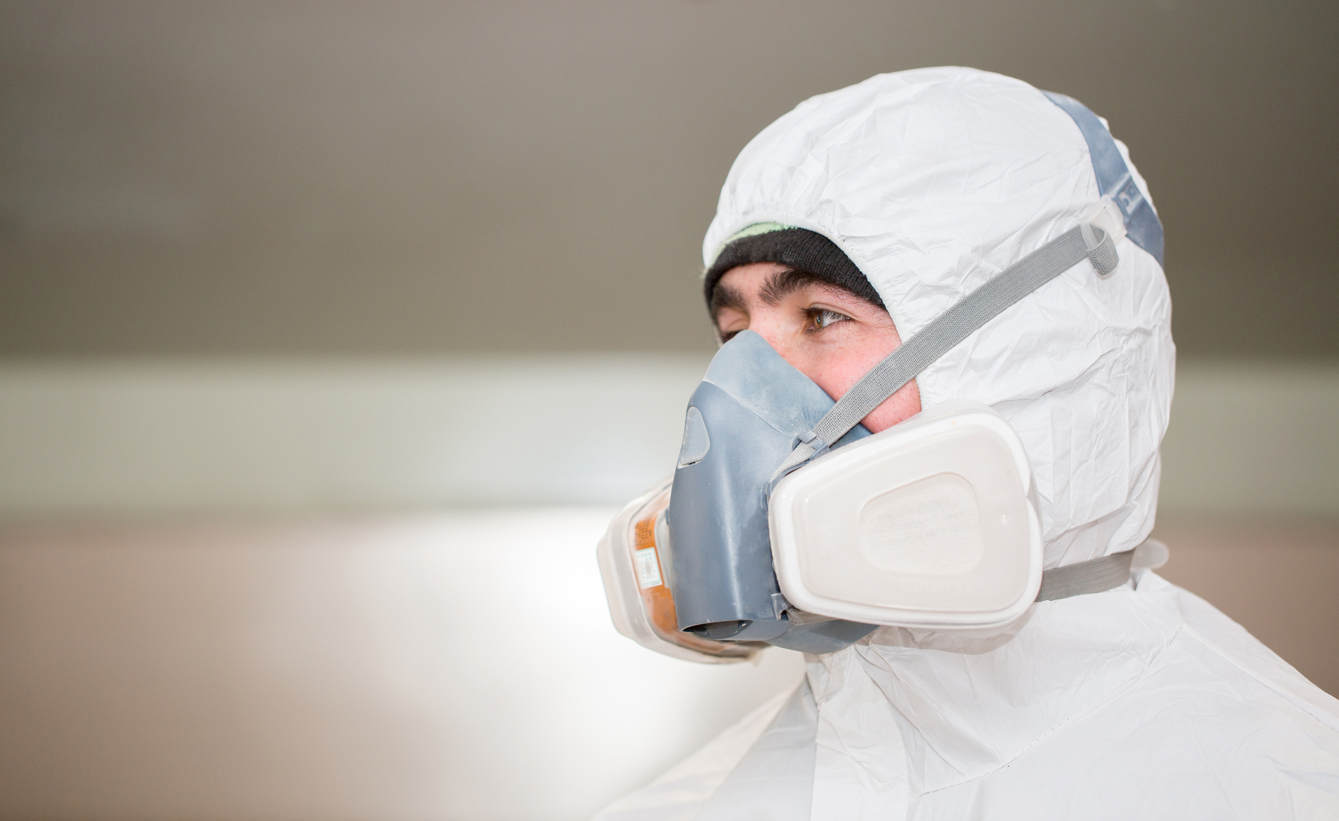 Wildlife technician in Tyvek suit and respirator preparing for dead animal removal in an Orlando attic